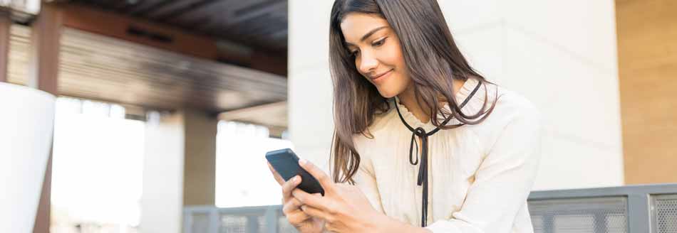 Eine junge Frau nutzt WhatsApp auf dem Smartphone