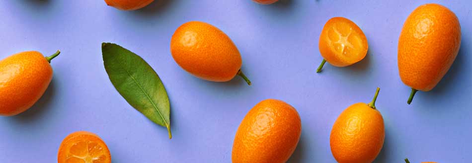 Viele Kumquats liegen auf hellblauem Grund