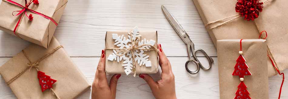 Geschenke verpacken: Frau hält ein Geschenk mit heller Schnur und Schneeflocke