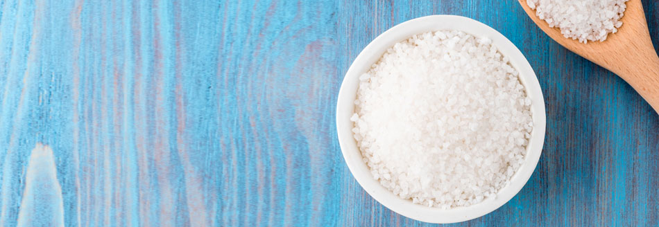 Wie viel Salz am Tag ist gesund: Eine Schale Salz mit einem Holzlöffel